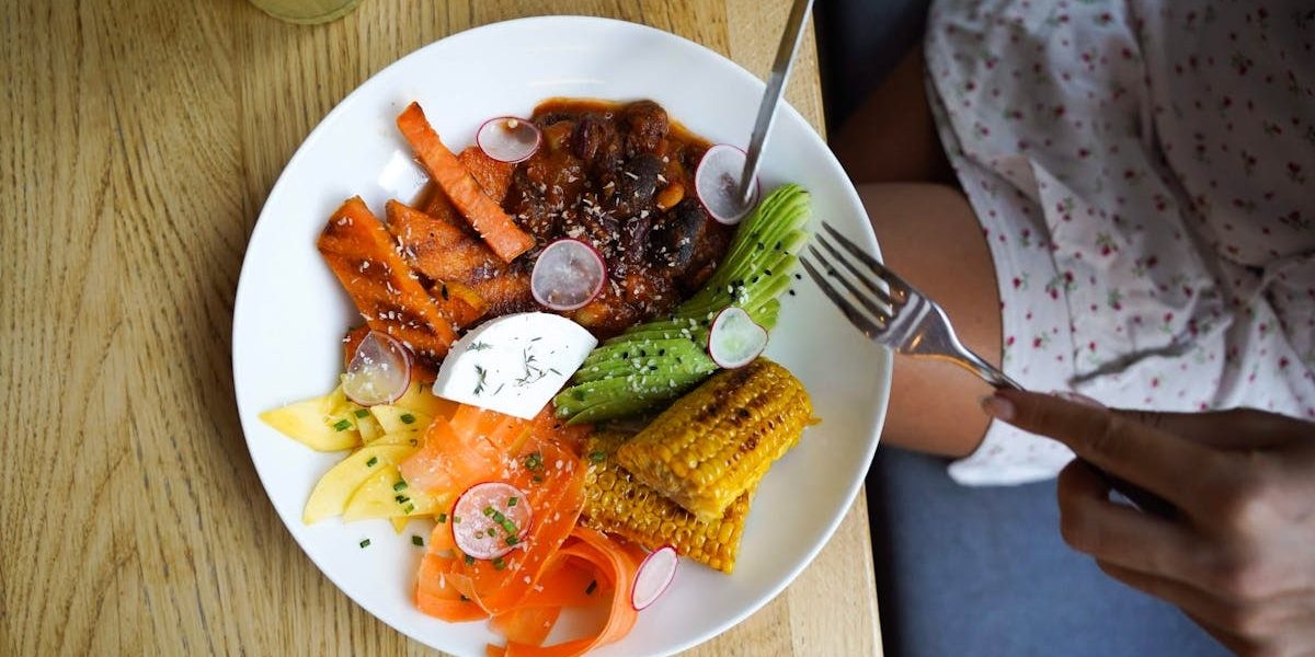 Colorful vegetarian meal with avocado, beans, and corn served on a wooden table. Ideal for healthy lifestyle visuals.