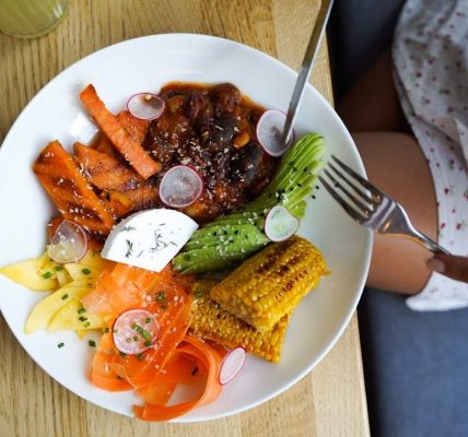 Colorful vegetarian meal with avocado, beans, and corn served on a wooden table. Ideal for healthy lifestyle visuals.