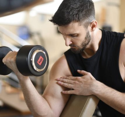Focused man lifting dumbbell, showcasing strength and fitness indoors.