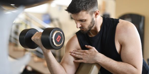 Focused man lifting dumbbell, showcasing strength and fitness indoors.